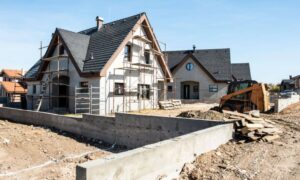 Construction survey stakes and bulldozer preparing a new subdivision site with homes being built
