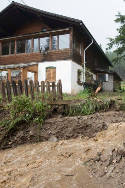 Home at risk from flooding and landslide erosion showing why a flood elevation survey is essential for property protection
