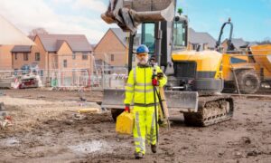 Land surveyor in safety gear walking across a muddy construction site after heavy rain, representing the importance of an ALTA Title Survey after storms