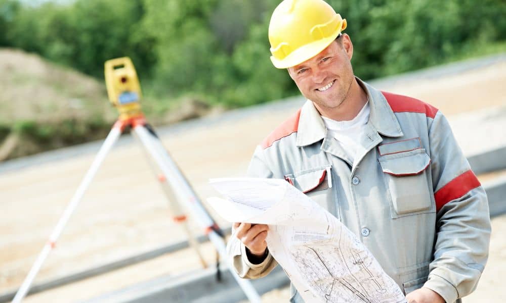 Surveyor holding site plans during an elevation survey with equipment set up to measure property height and flood risk

