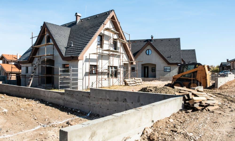 Construction survey stakes and bulldozer preparing a new subdivision site with homes being built
