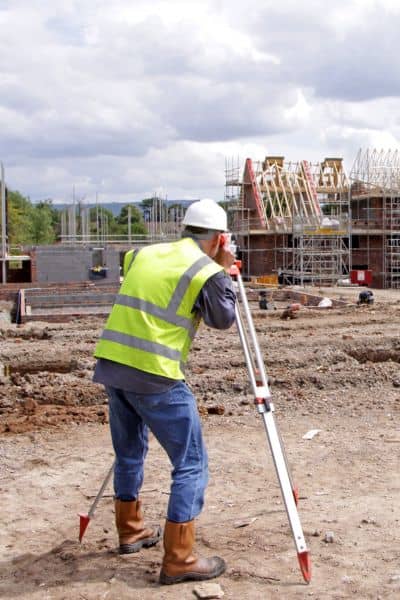 Surveyor performing a construction survey with equipment on a new subdivision site

