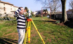 Land surveyor using total station to measure property boundaries during an ALTA Land Title Survey