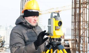 Build site surveyor equipment - ALTA SURVEY South Carolina Surveyor using a total station during a construction survey on a busy job site