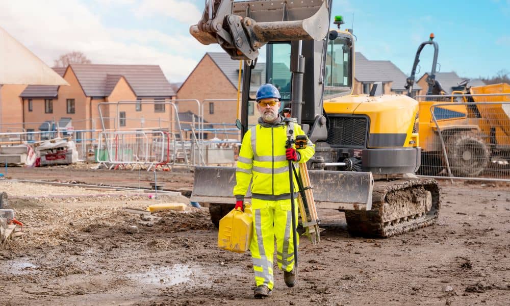 Land surveyor in safety gear walking across a muddy construction site after heavy rain, representing the importance of an ALTA Title Survey after storms