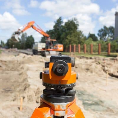 Surveyor using equipment at a construction site, illustrating a subdivision survey process