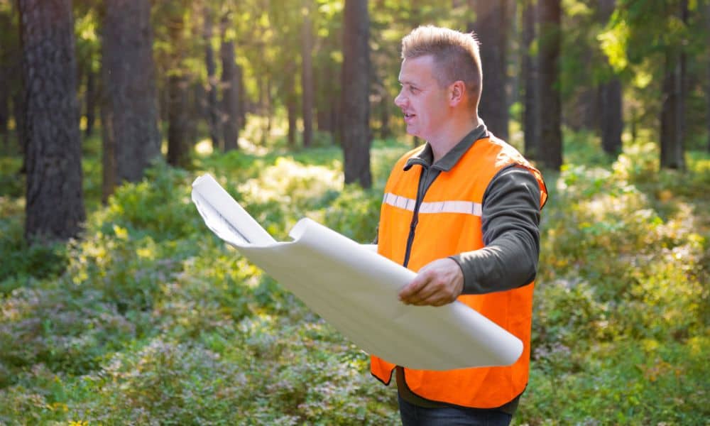 Surveyor comparing a plat map to the land as part of a boundary line survey