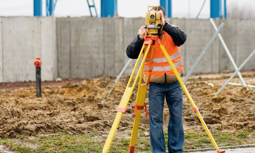 Surveyor using a total station on a construction site performing a topographic survey