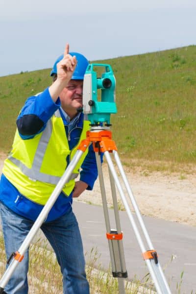 Land surveyor using total station field work - ALTA SURVEY South Carolina Surveyor using equipment to measure land conditions a land survey company reviews before development