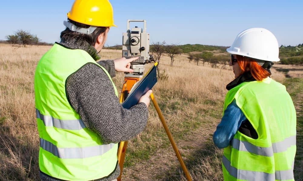 Surveyors measuring a residential lot with total station equipment before adjusting property boundaries